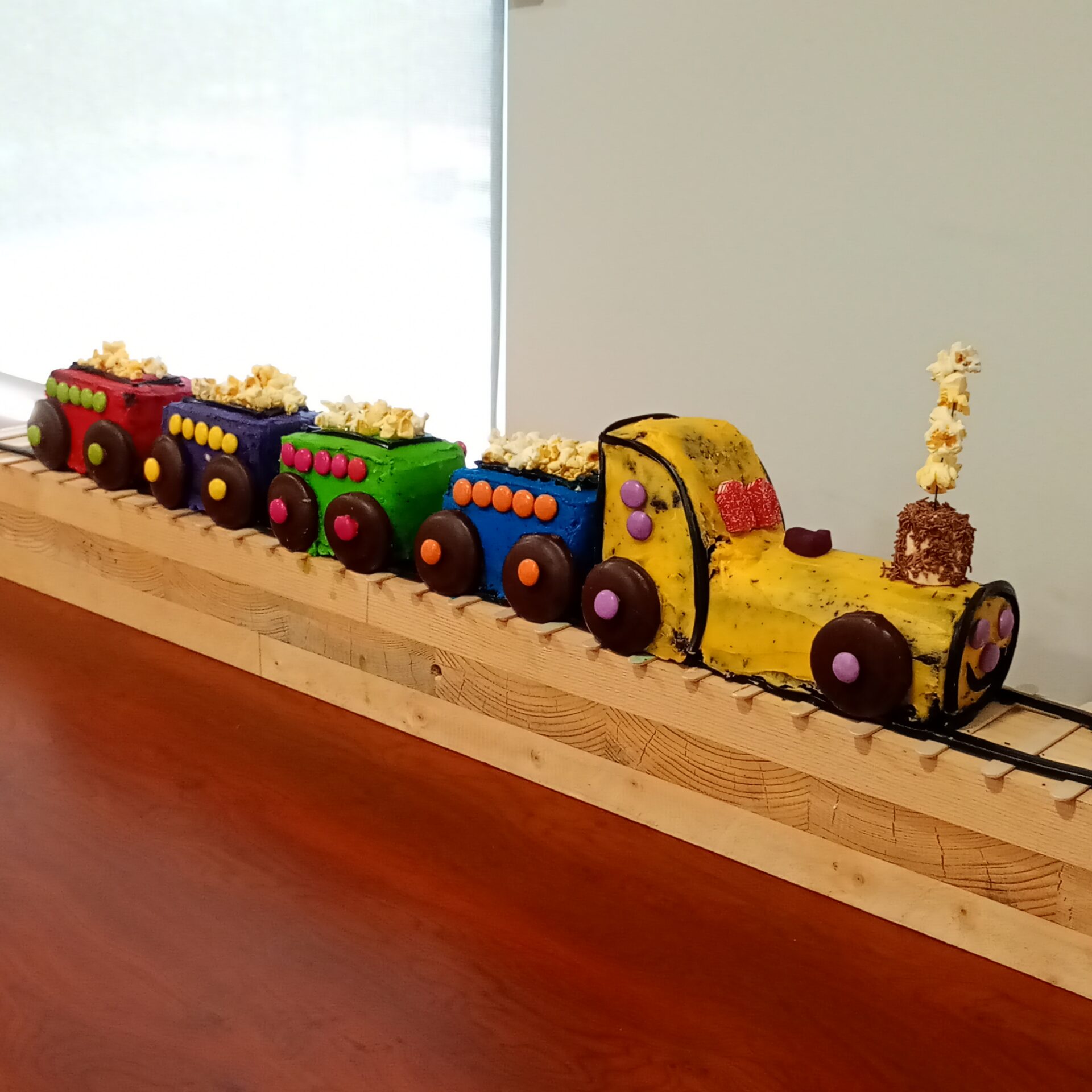 A cake made to look like a train with carriages on a wooden track