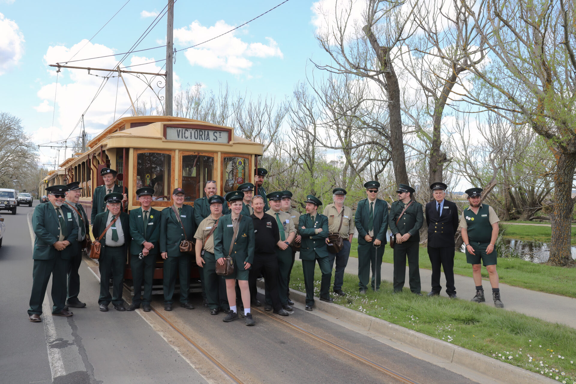 Large group of volunteer tram crews standing in front of a tram