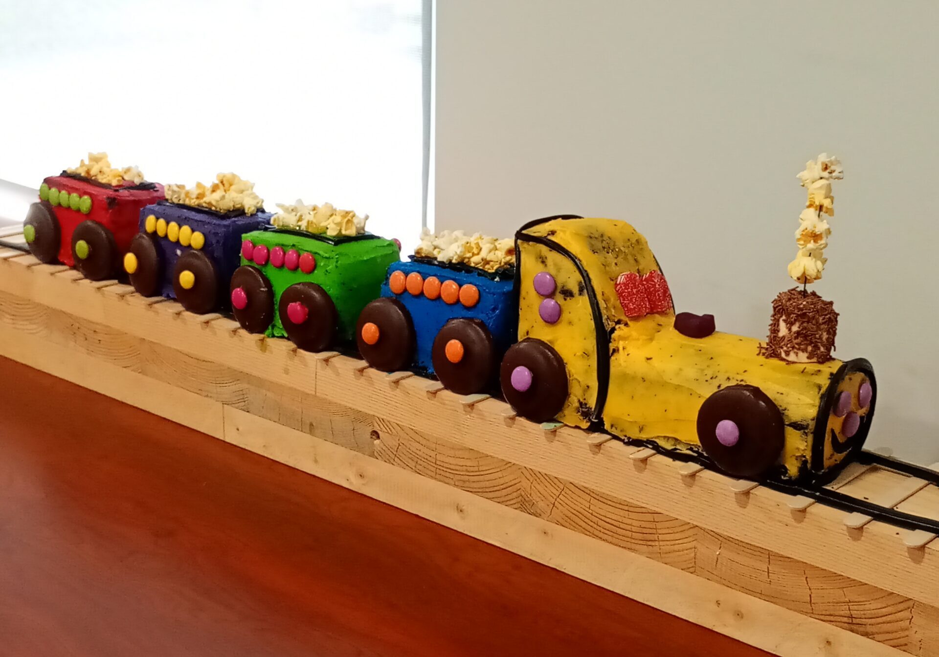 A cake made to look like a train with carriages on a wooden track